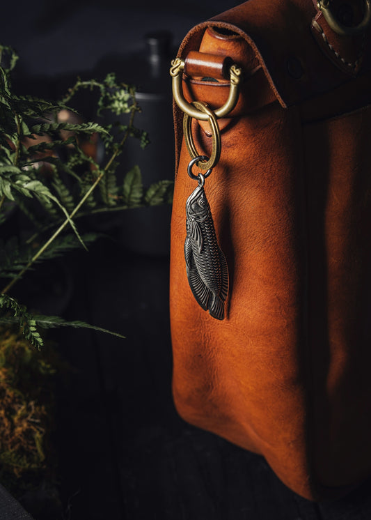 a brown leather bag with a feather charm hanging from it