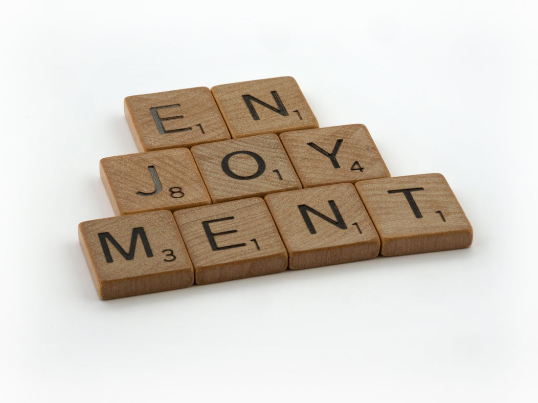 a scrabble of wooden blocks spelling the words enjoy joy, joy, and