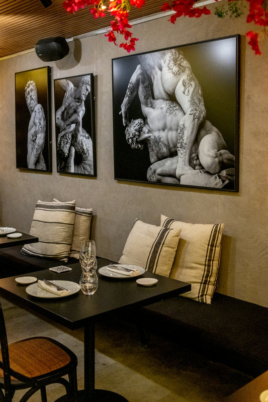 Three framed artworks of muscular figures hang on wall.