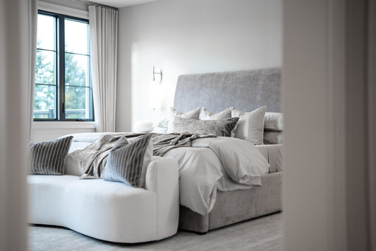 A modern bedroom with a large bed and white bench.